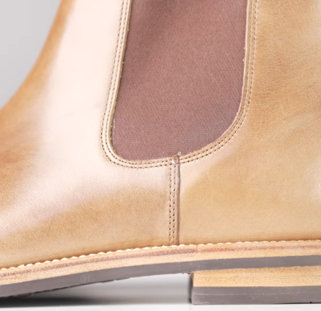 Vidéo d'examen des bottines Chelsea, point culminant 1 Gros plan d'une botte Chelsea en cuir marron montrant le panneau latéral élastique marron, les coutures cousues et la trépointe à l'endroit où la tige rencontre la semelle.