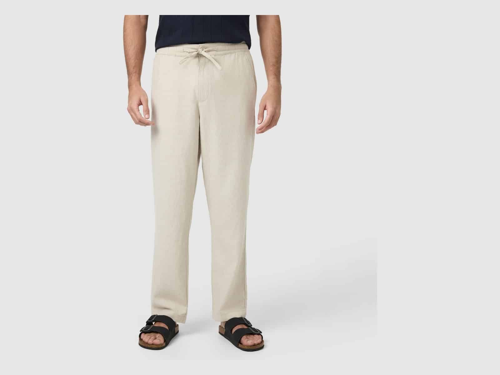 Le pantalon Connor Cabana en mélange de lin en sable porté avec un haut bleu marine et des sandales à glissière noires