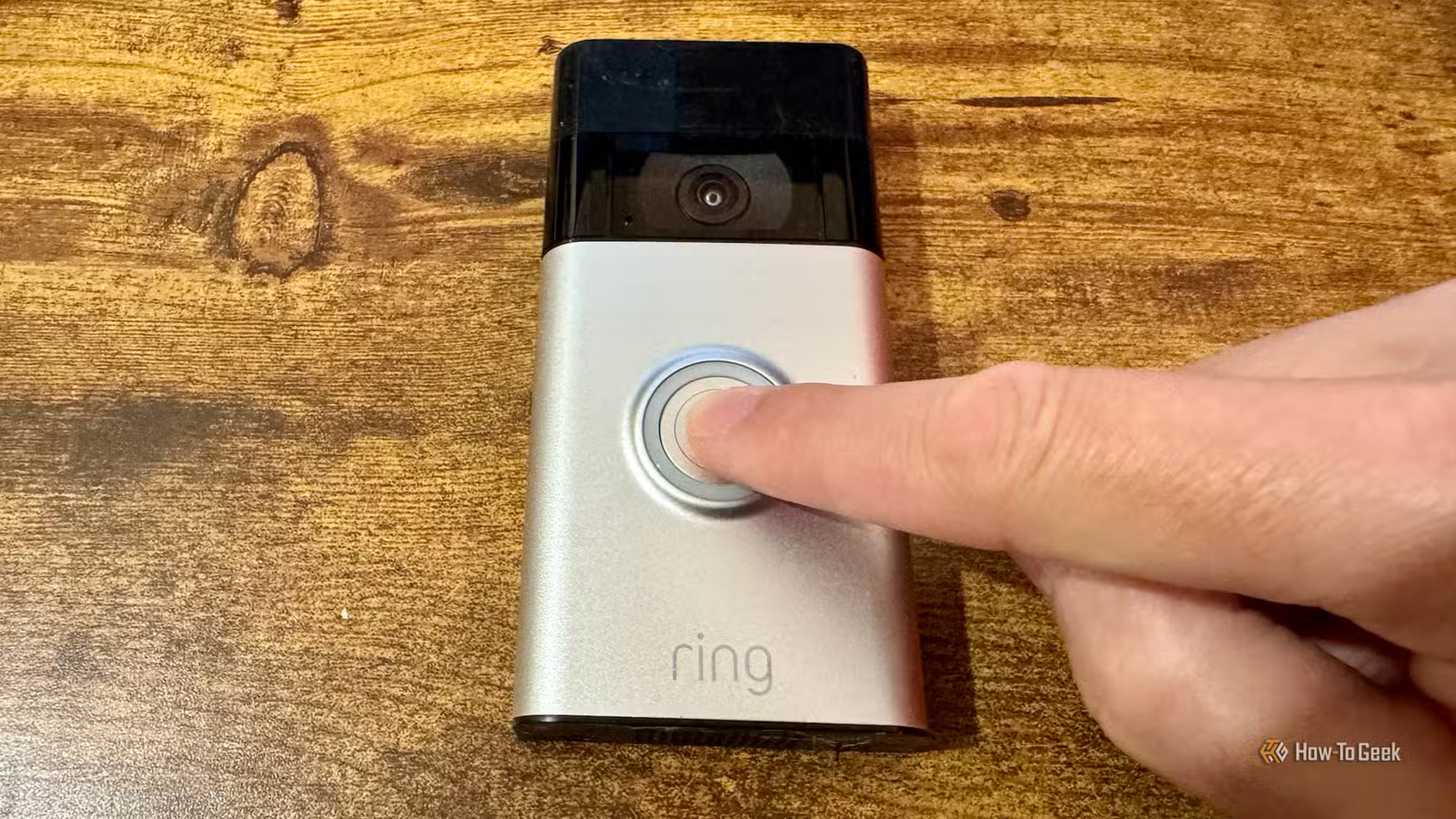 Un doigt a appuyé sur le bouton de sonnerie d’une sonnette vidéo Ring sur un bureau.