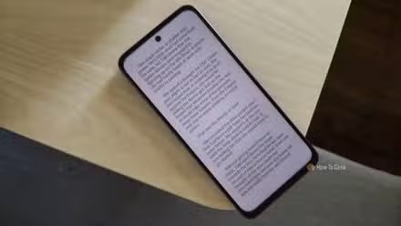 Smartphone Android TCL NXTPAPER 70 Pro sur le bord d'une table en bois.