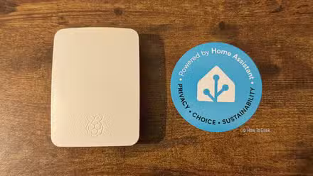 Un Rasbperry Pi dans un étui officiel Raspberry Pi à côté d'un autocollant Home Assistant.