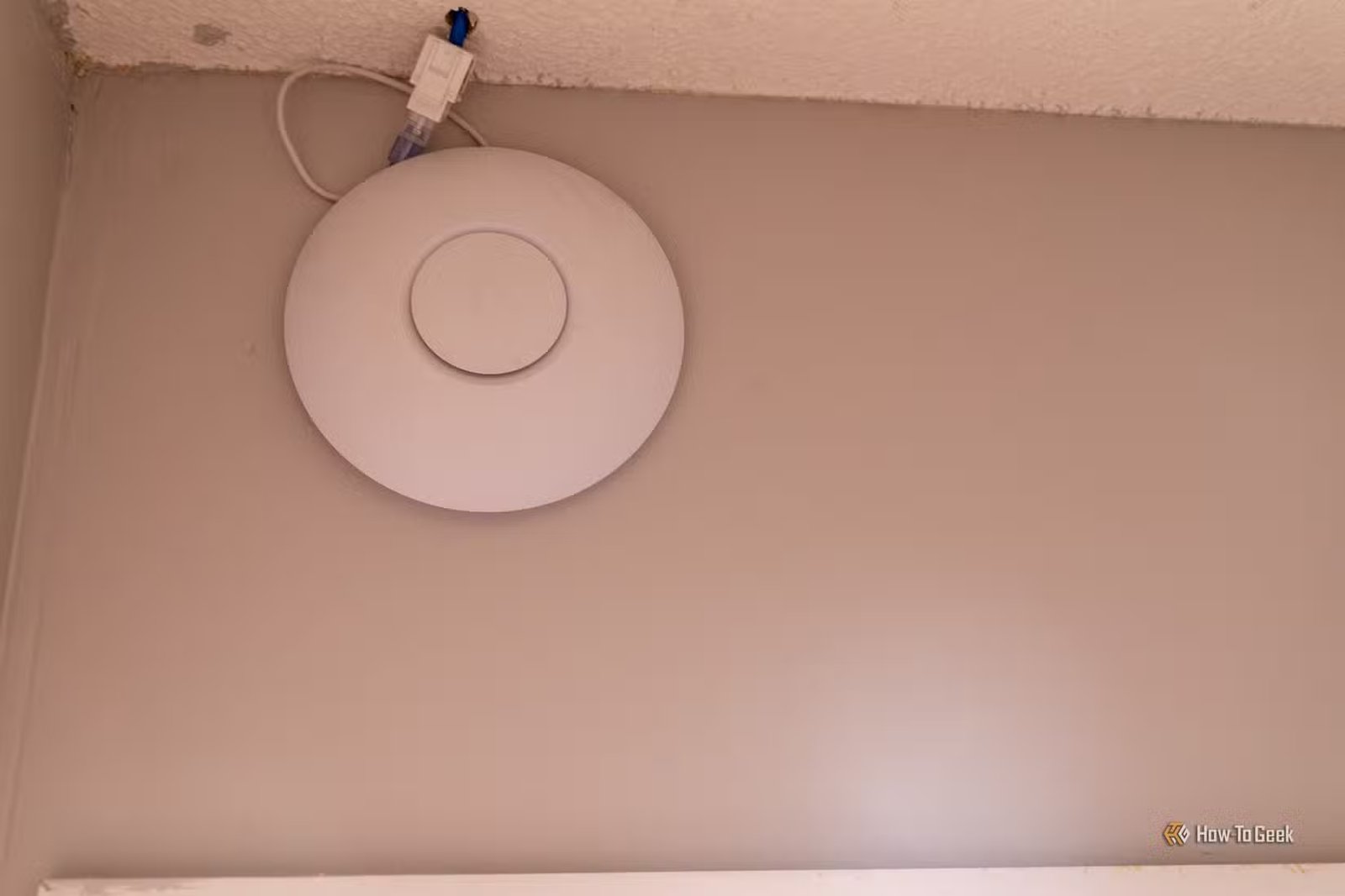 Point d'accès sans fil monté au plafond connecté à une prise murale Ethernet.