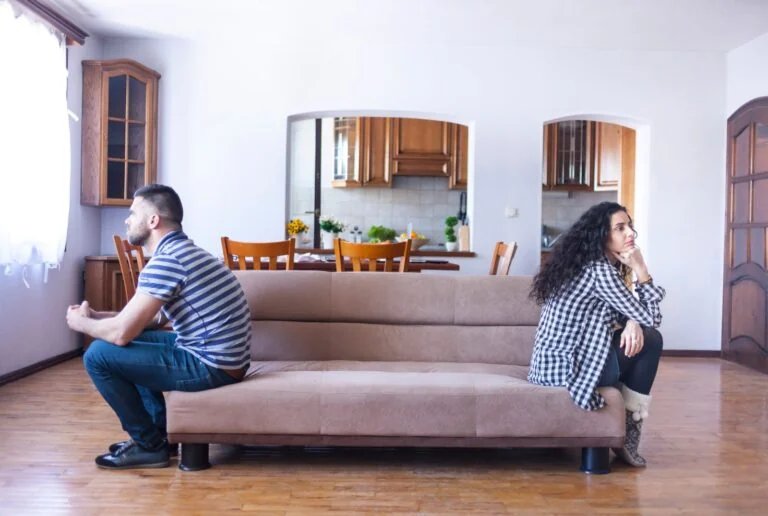 Couple assis dos à dos sur un canapé à la maison