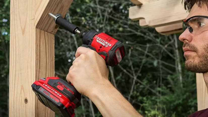 Un homme enfonçant un tire-fond dans une structure en bois avec une perceuse Craftsman.